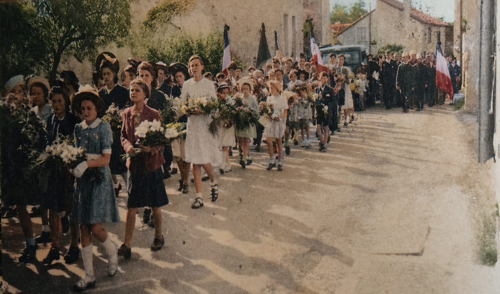 Village girls in summer dresses carrying armfuls of flowers lead the funeral procession through Loches-sur-Ource