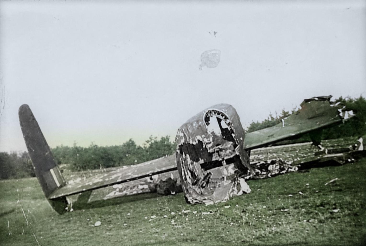 The tail section of ND994 lying on short grass, the turret opening empty, the fin with its roundel to the left, trees behind